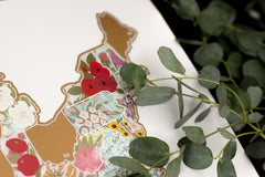 Decorative stickers shaped like a map with floral patterns on a white surface with green leaves.