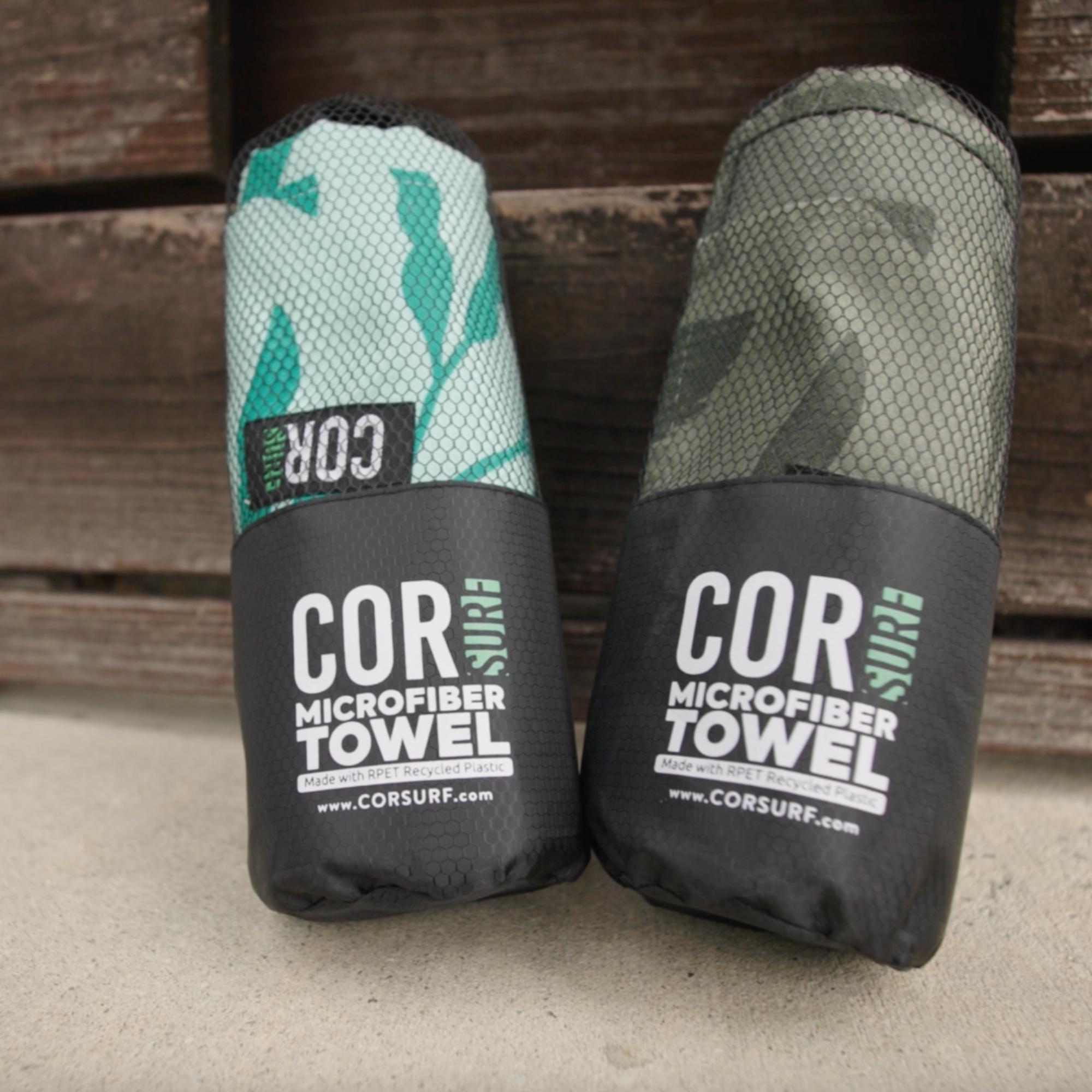 Two COR microfiber towels in green and black packaging on a wooden surface.
