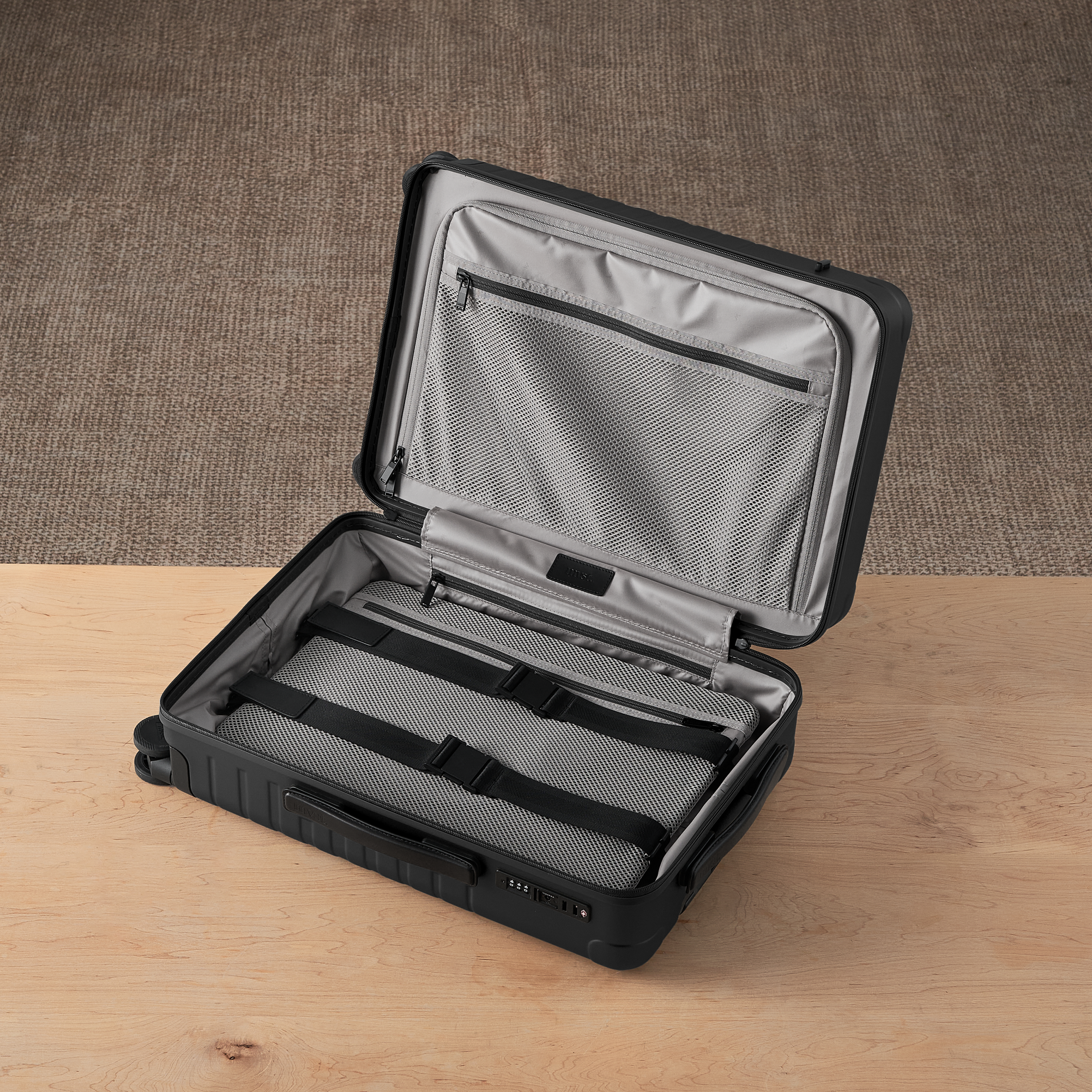 Open black suitcase with gray interior on a wooden surface