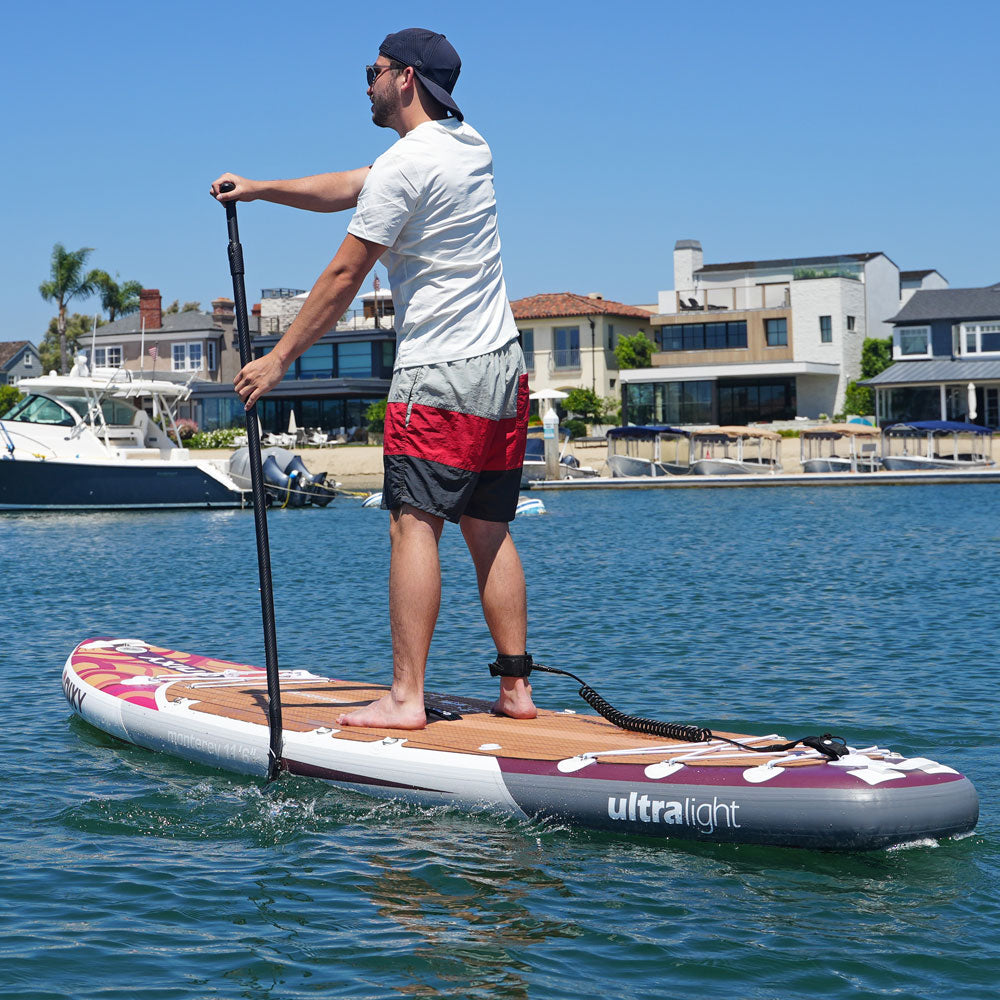 Man paddleboarding on a body of water with houses and boats in the background