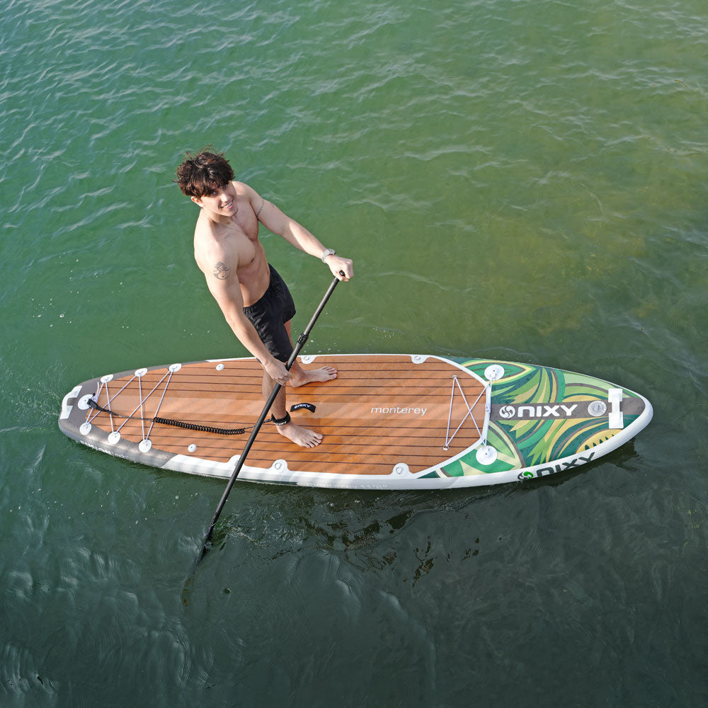 Man paddleboarding on a body of water with a NIXY board and paddle.