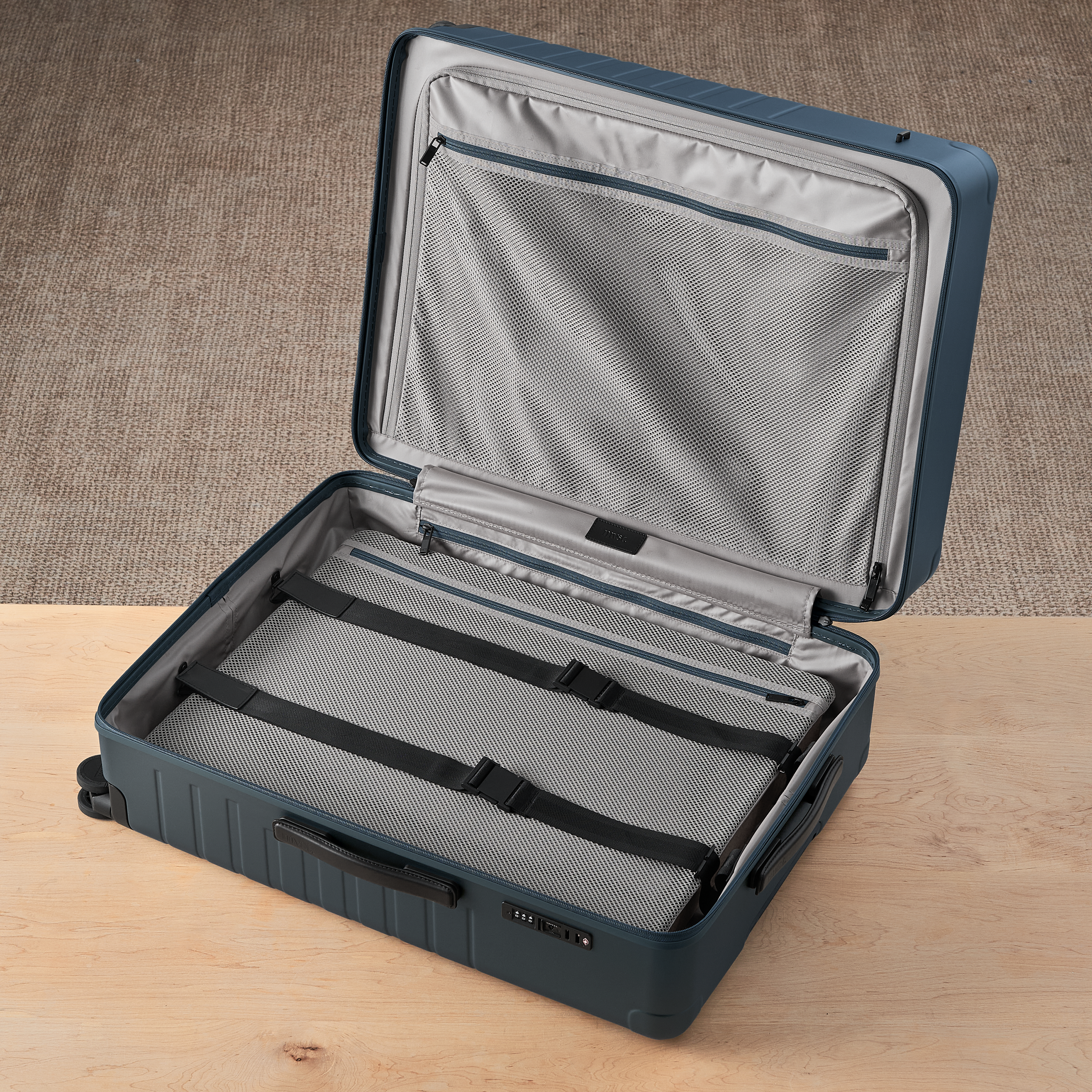 Open blue suitcase with gray interior on a wooden surface