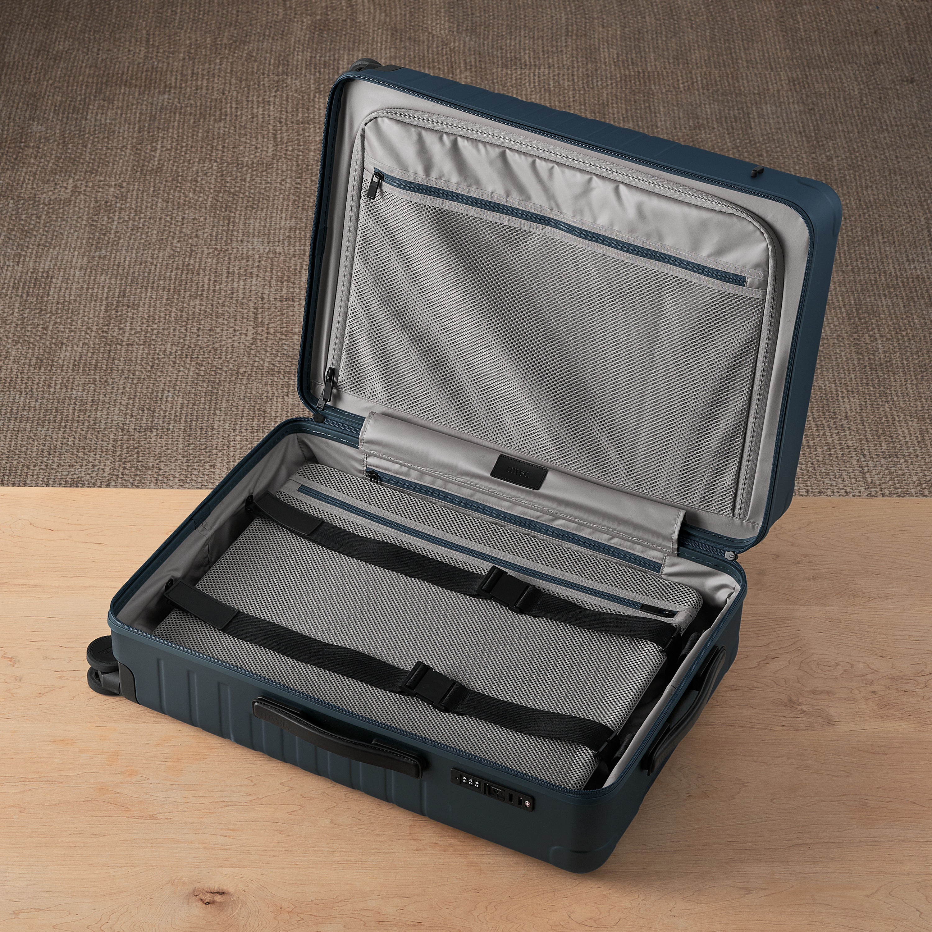 Open blue suitcase with gray interior on a wooden surface