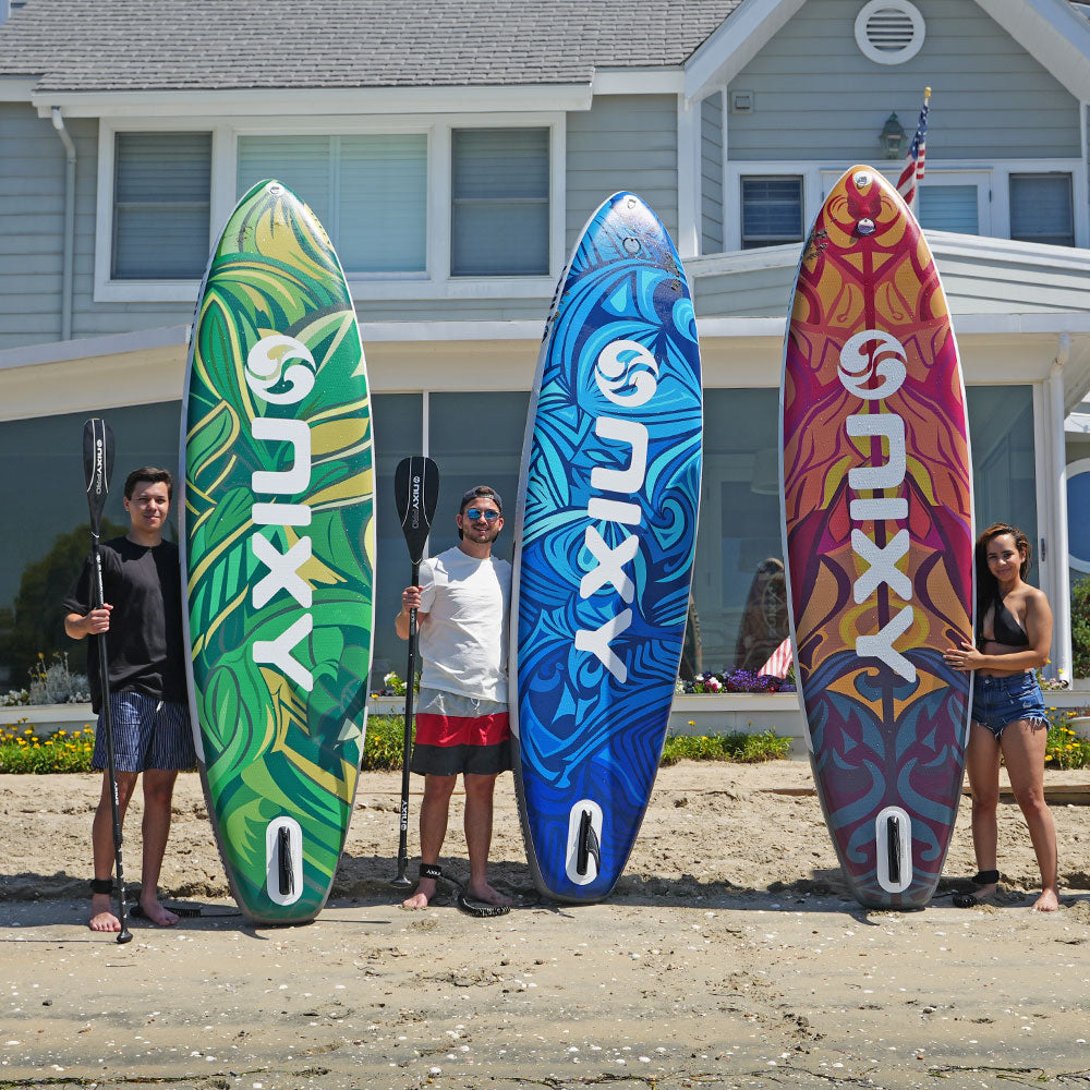 Three people holding colorful surfboards with 'Nixy' branding on a beach.