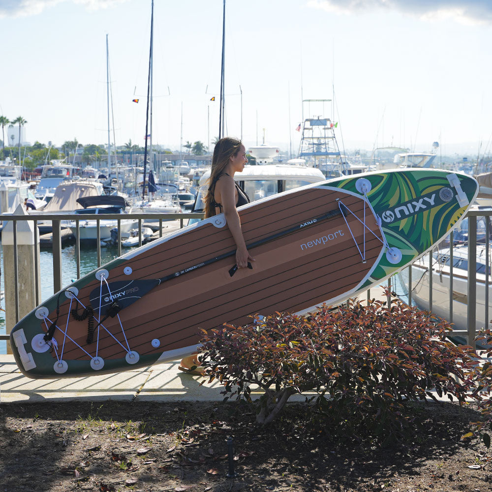 Person holding a large surfboard with 'Onxy' branding at a marina.