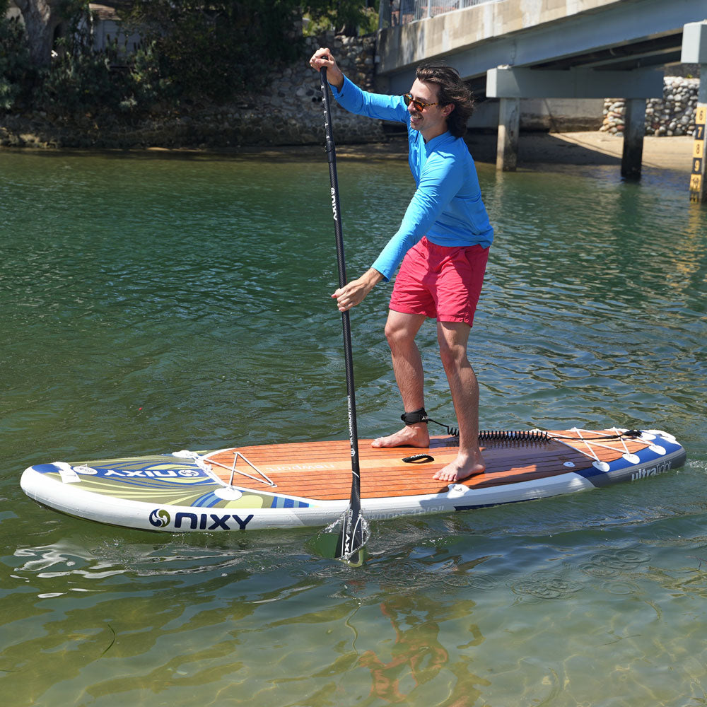 Person paddleboarding on a body of water with a bridge in the background