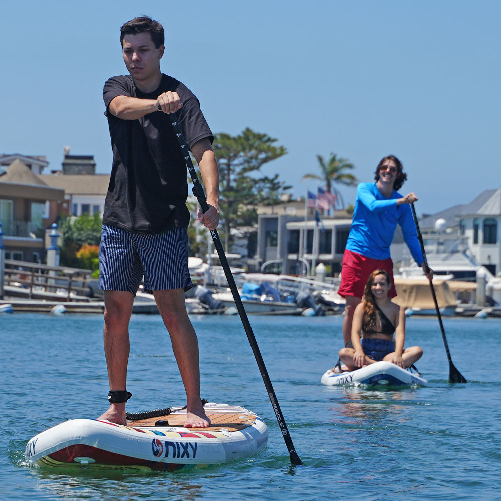 Three people paddleboarding on a body of water with a marina in the background.