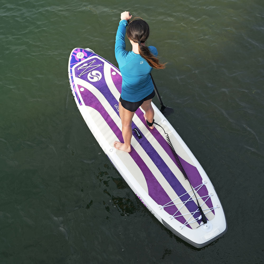 Person paddleboarding on a purple and white board in green water