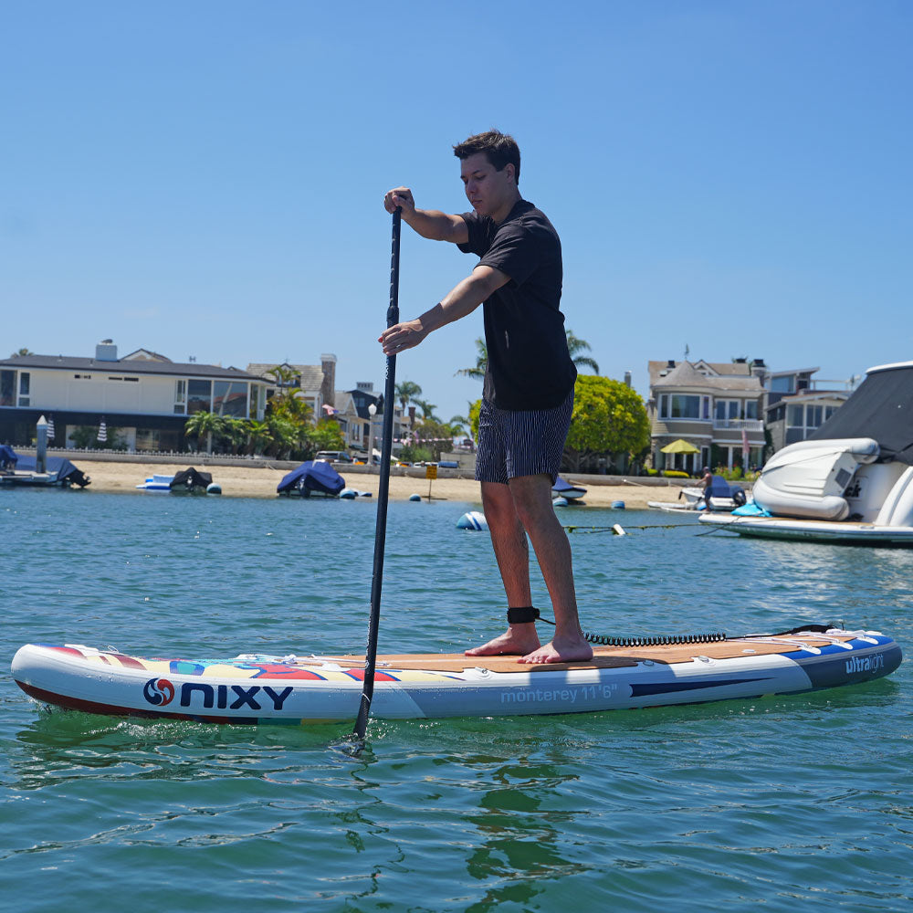 Person paddleboarding on a body of water with buildings and boats in the background