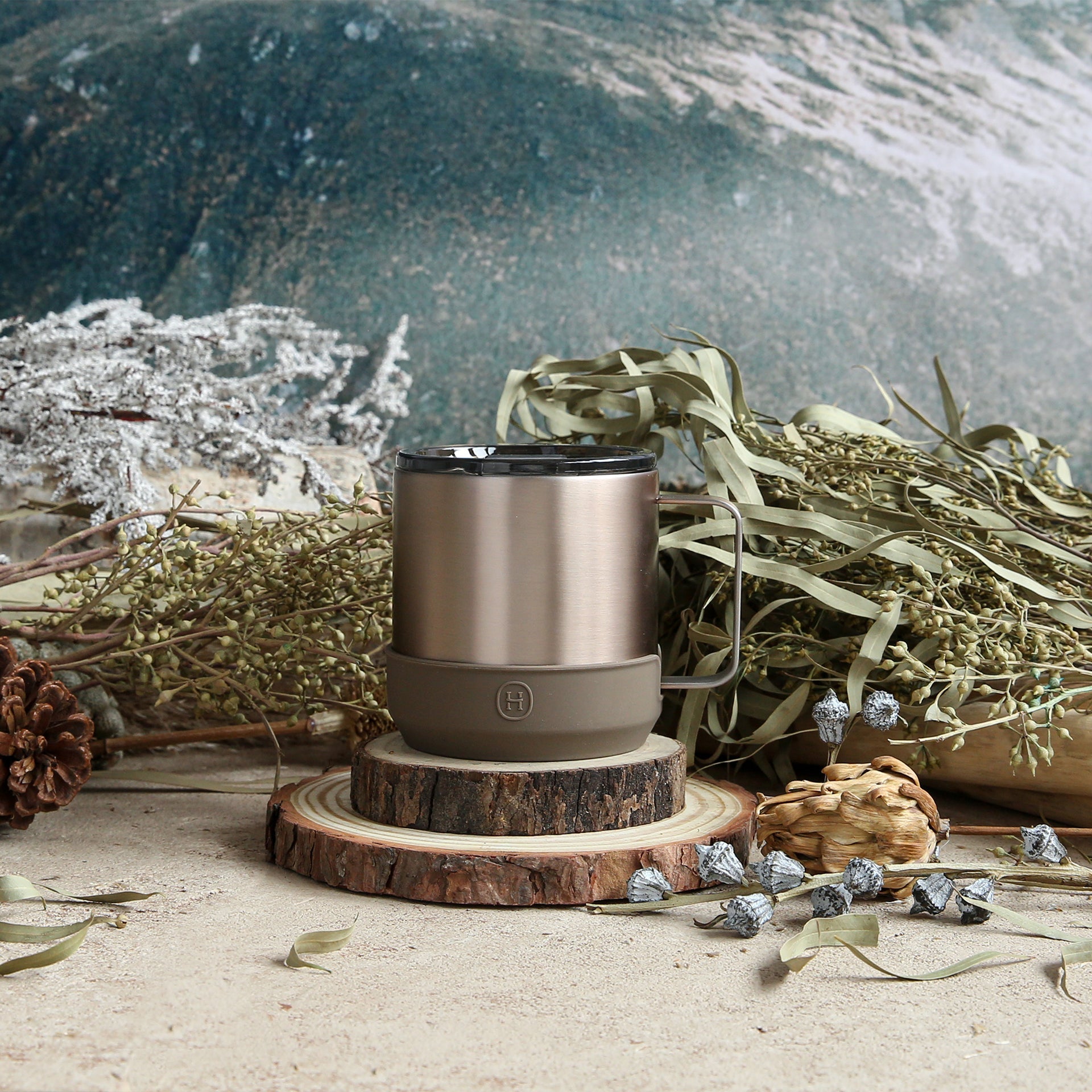 Brown insulated mug on a wooden coaster with nature-themed background