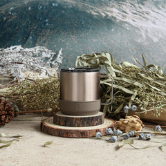 Brown insulated mug on a wooden coaster with nature-themed background
