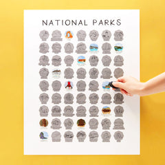 Collection of national park pins on a poster with a hand holding a pin against a yellow background