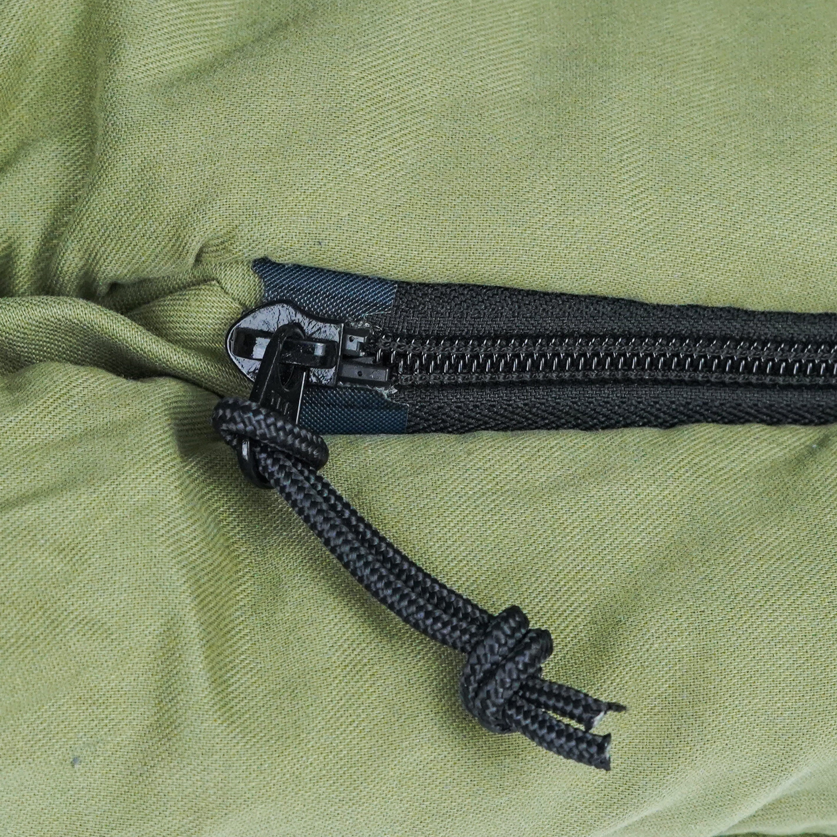 Close-up of a black zipper on green fabric