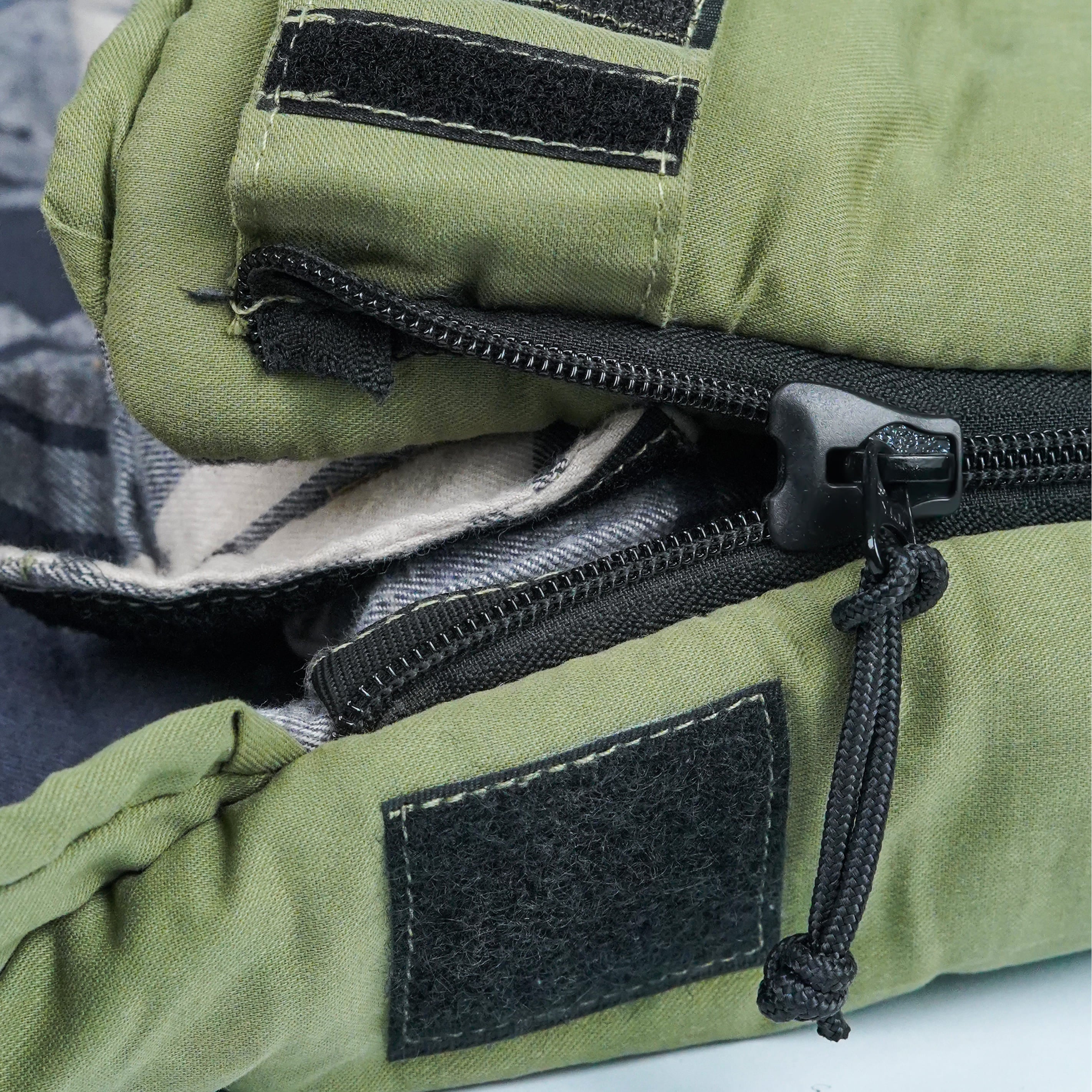 Green military-style bag with zippers and patches on a gray background