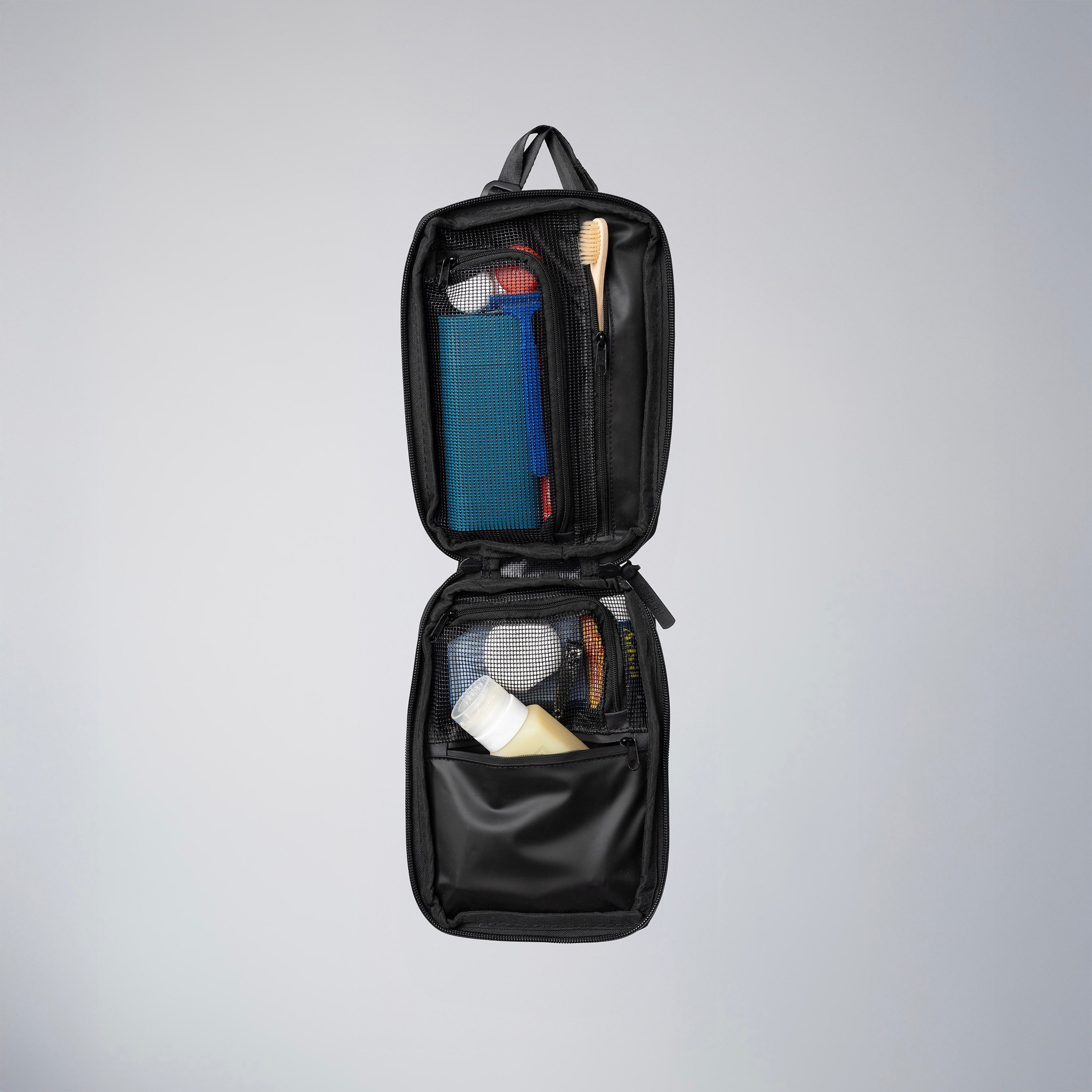 Black toiletry bag with organized compartments on a gray background