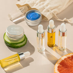 Skincare products including bottles, jars, and a cucumber slice on a neutral background