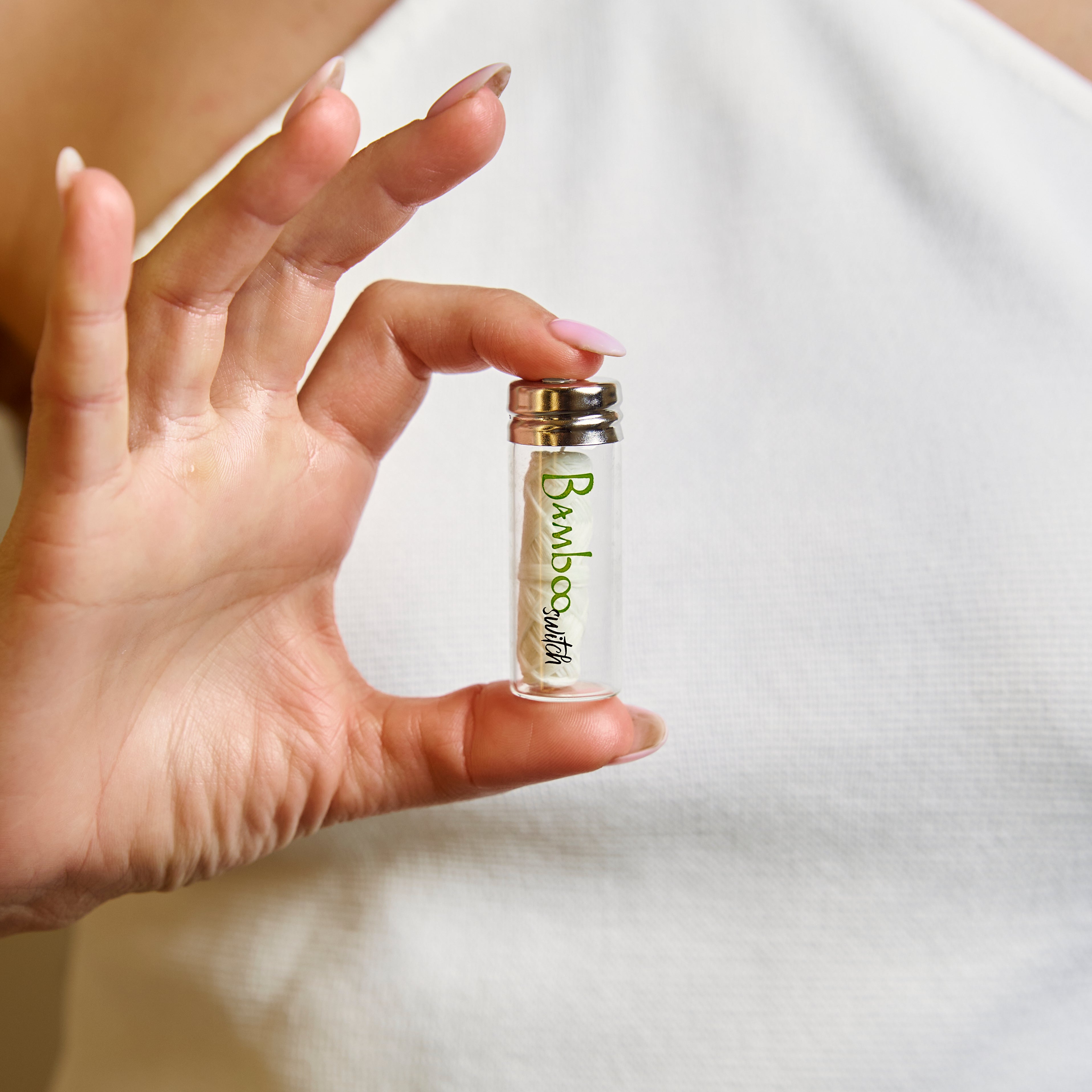 Hand holding a small glass bottle labeled 'Bamboo' against a white background