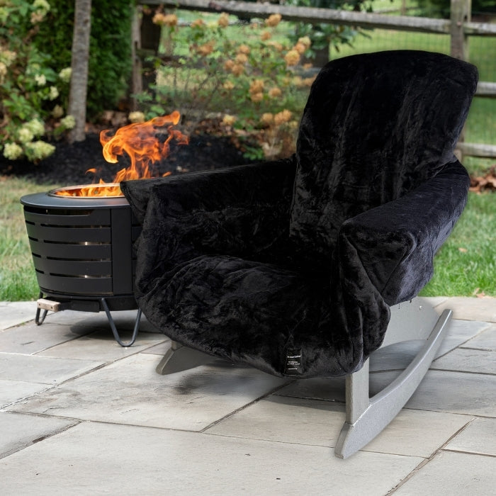 Black plush chair on a stone patio with a fire pit in the background