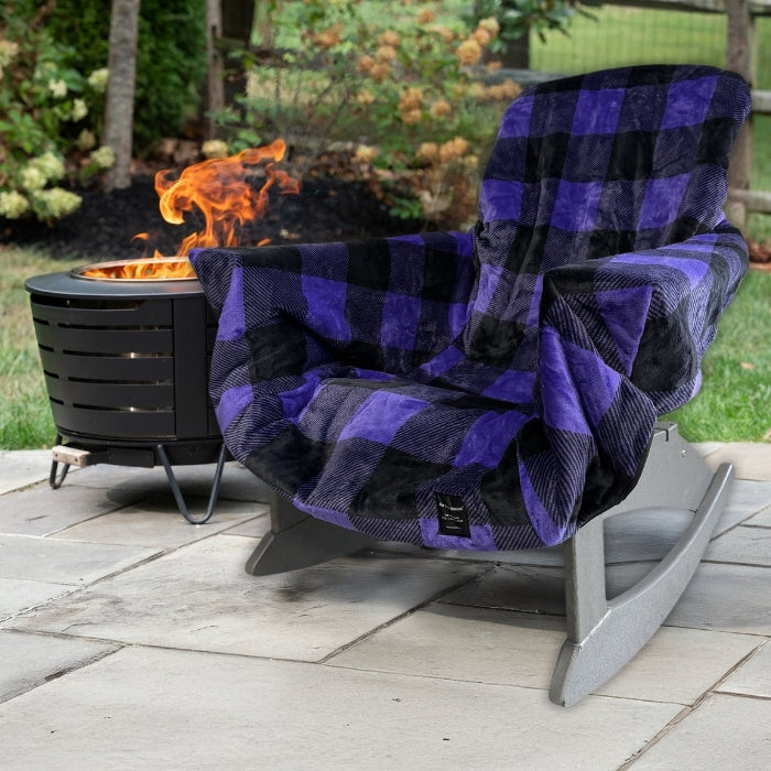 Plaid blanket draped over a chair next to a fire pit in an outdoor setting