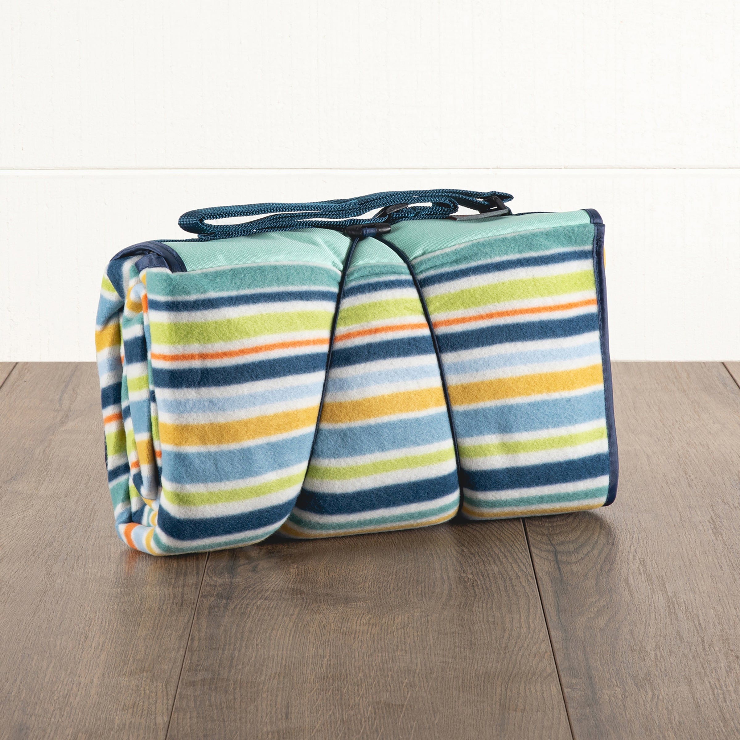 Striped picnic blanket with carrying handle on a wooden floor
