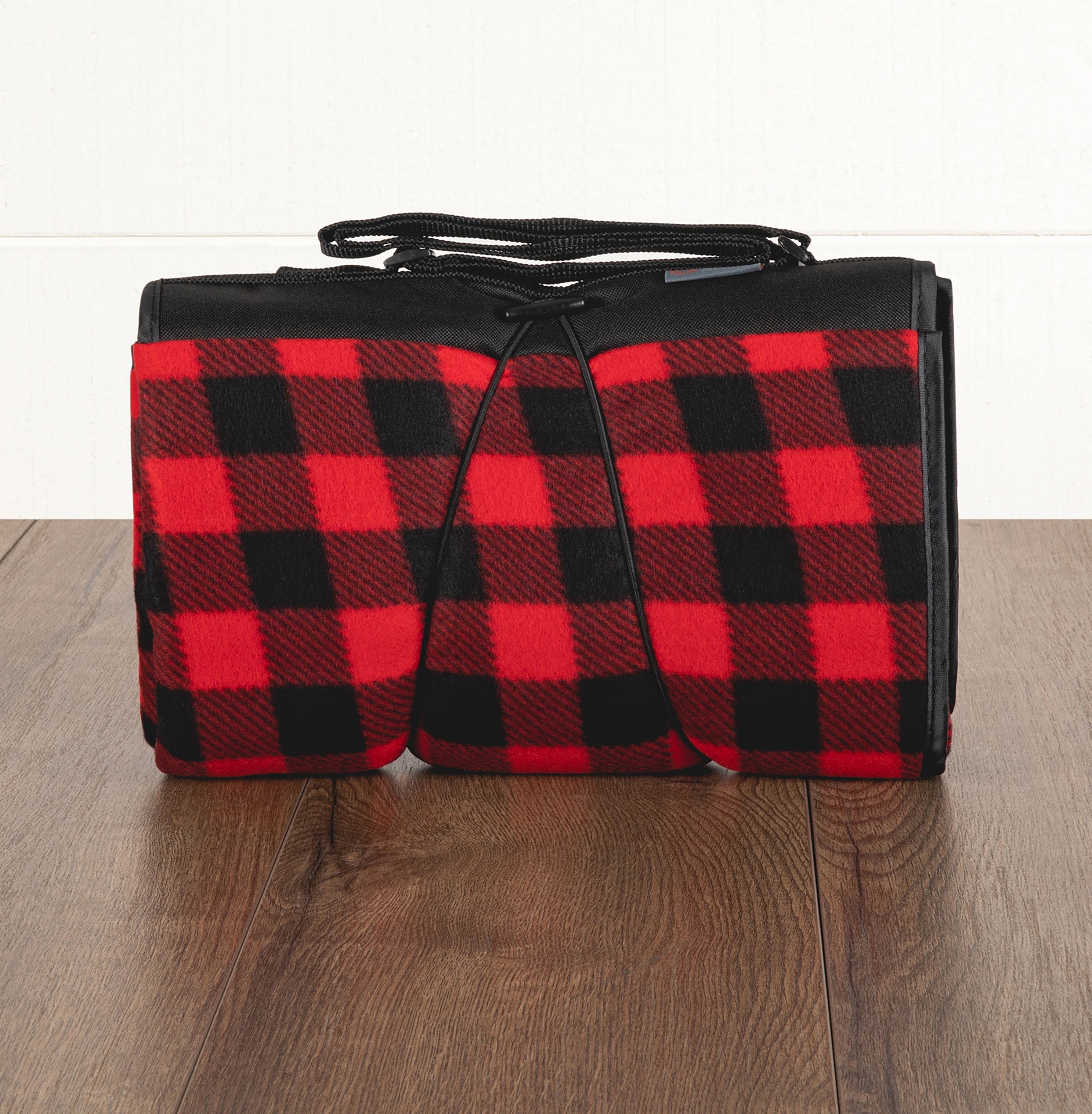 Red and black checkered blanket with a black border on a wooden floor.