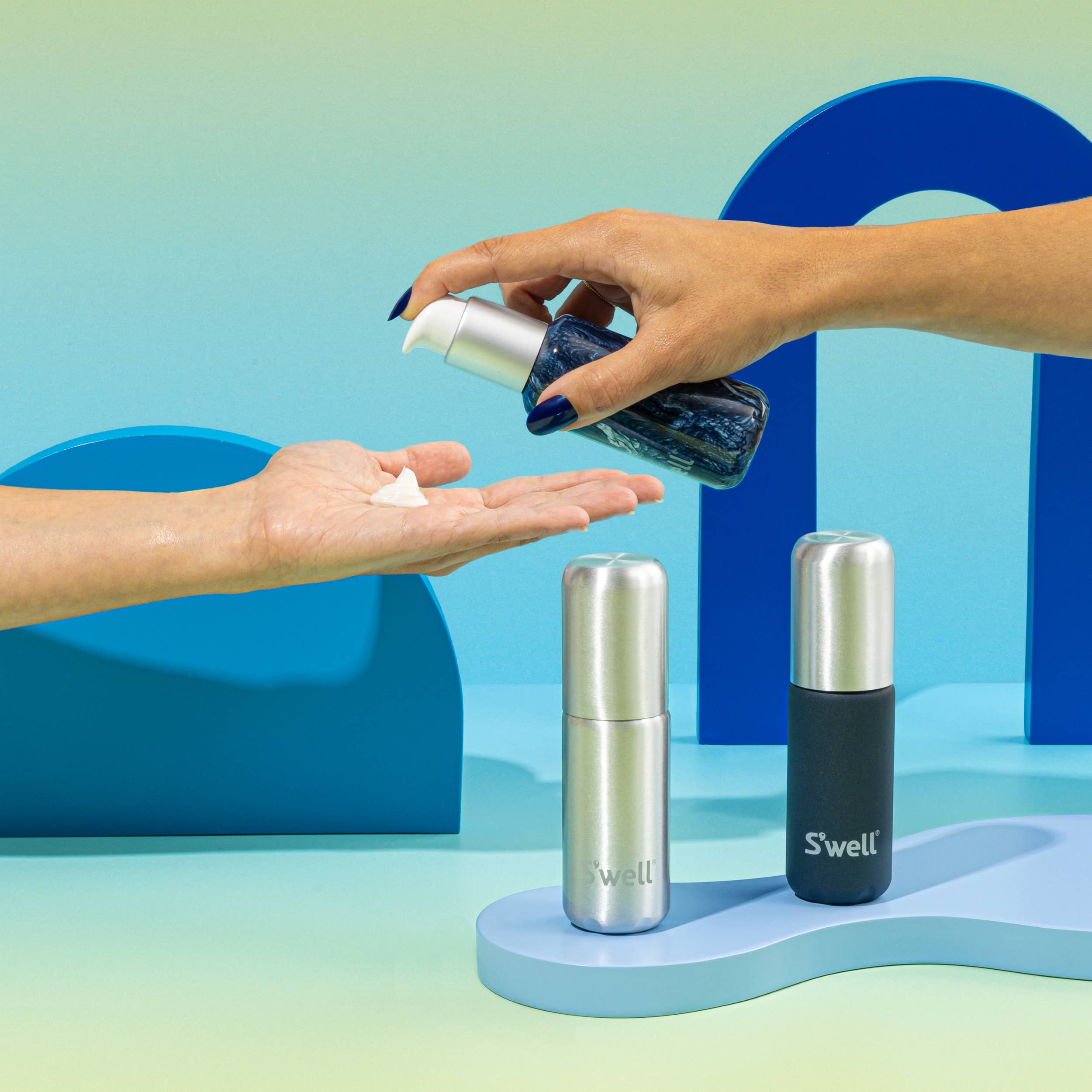 Person applying cream to hand with S'well bottles on colorful background
