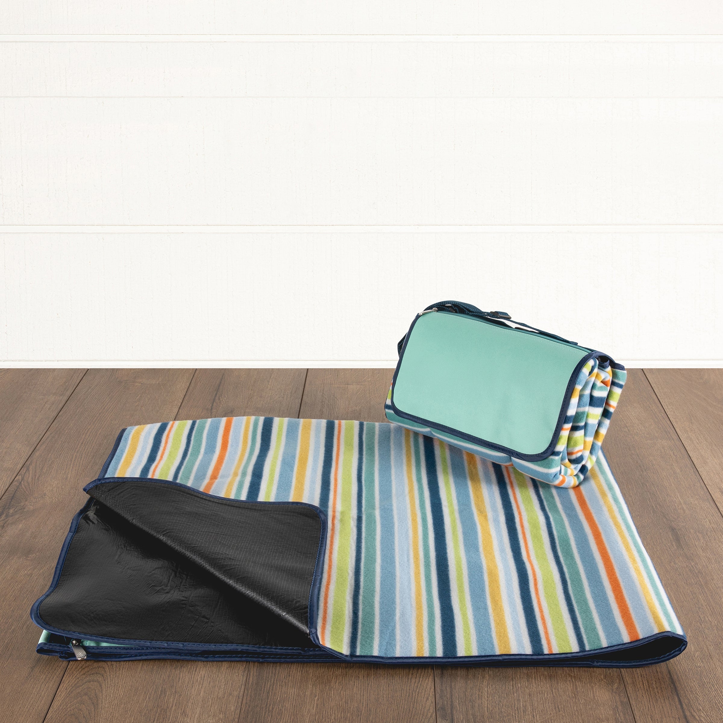 Striped picnic blanket with a green bag on a wooden surface