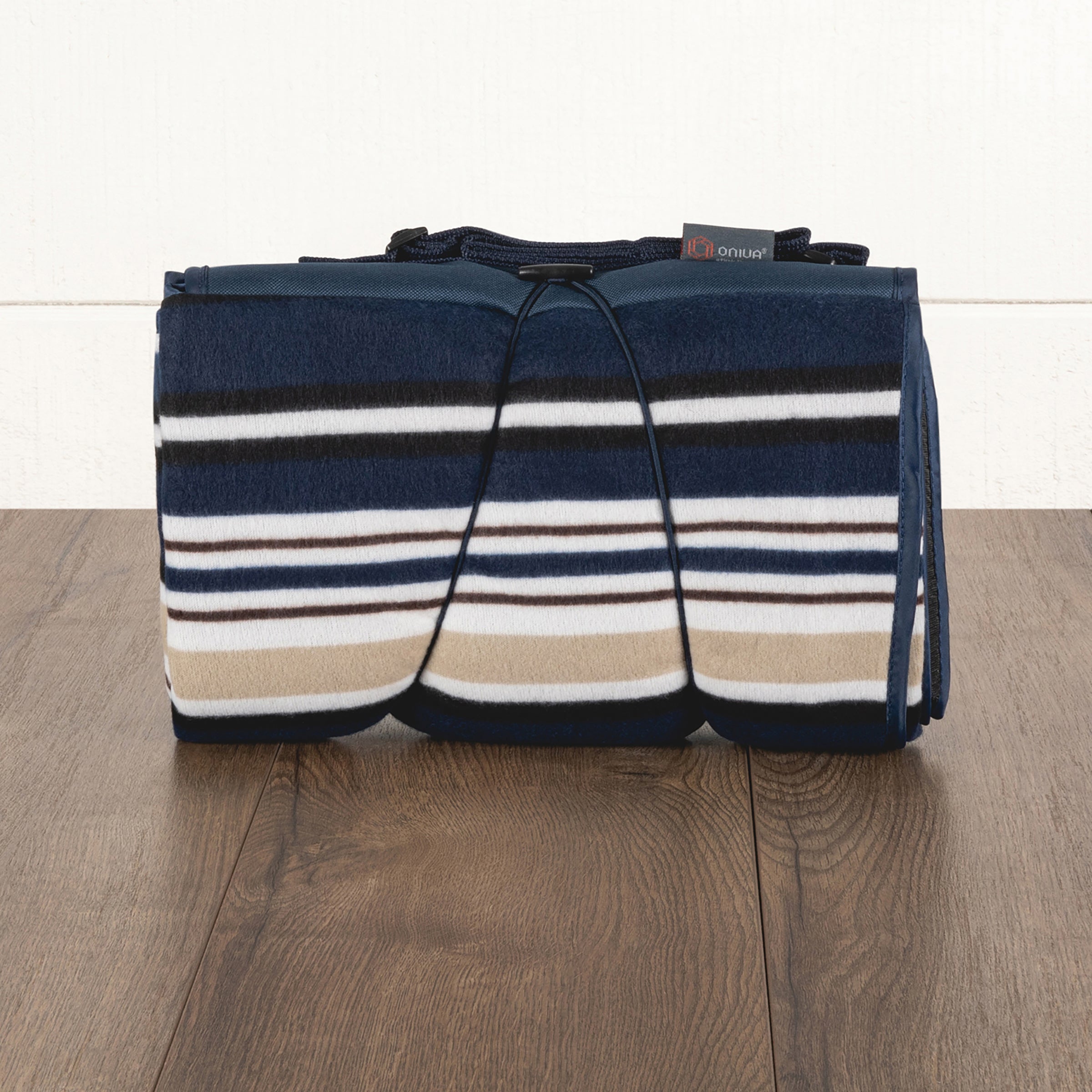 Striped picnic blanket with a brand label on a wooden surface