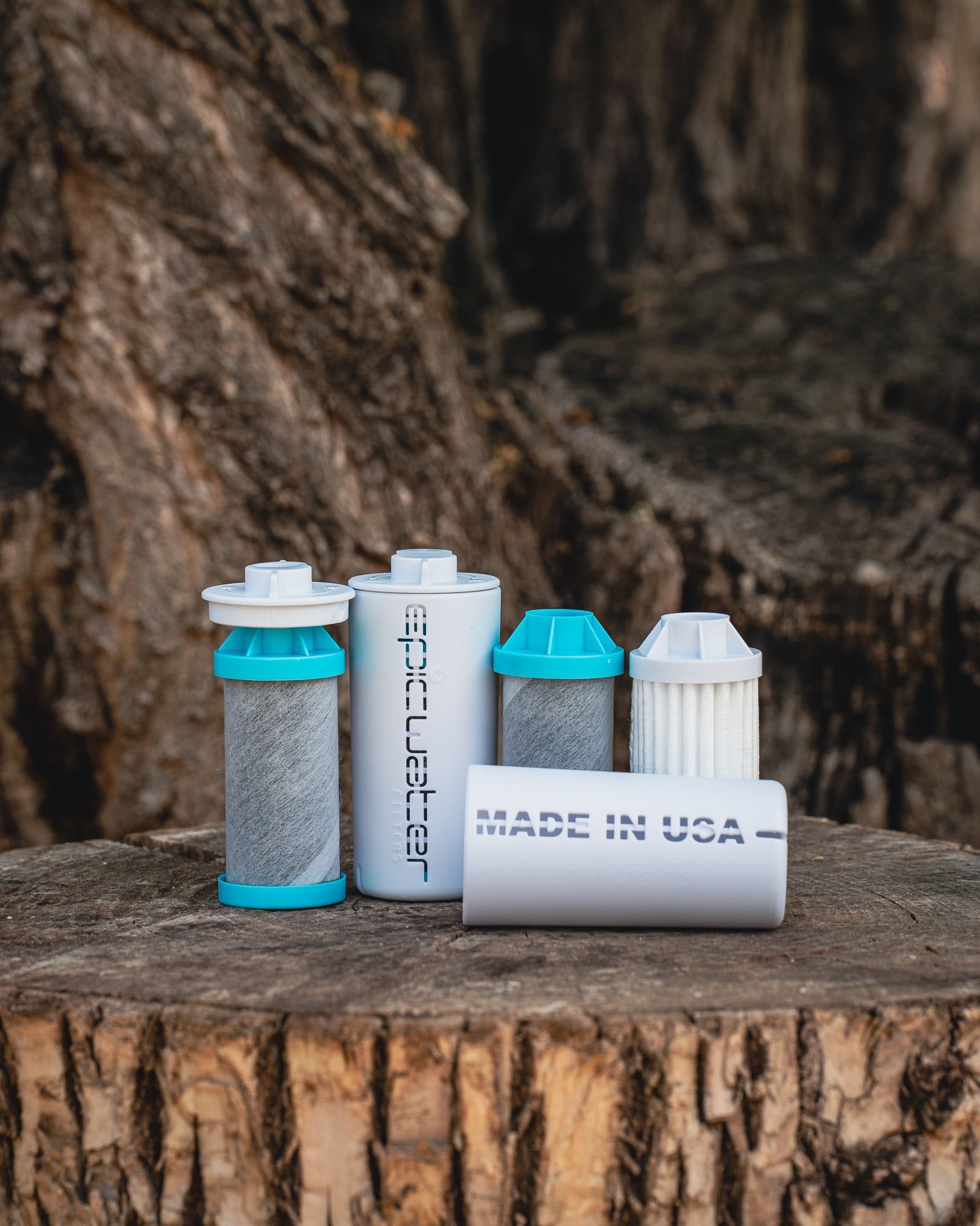 Water filter cartridges on a wooden stump with a tree trunk background