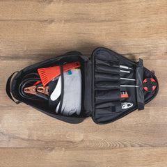 Open tool bag with tools and equipment on a wooden surface