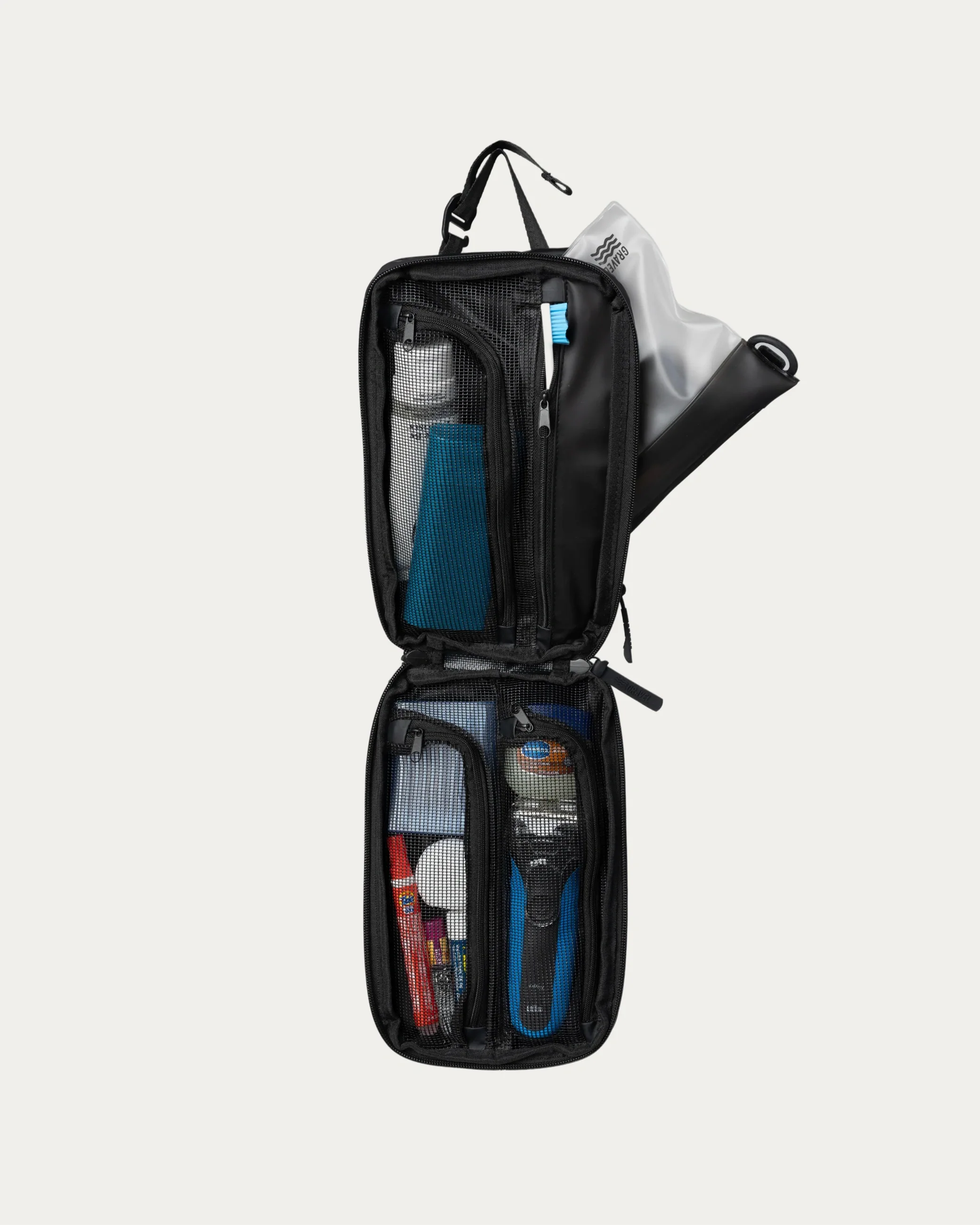Black toiletry bag with travel items on a white background