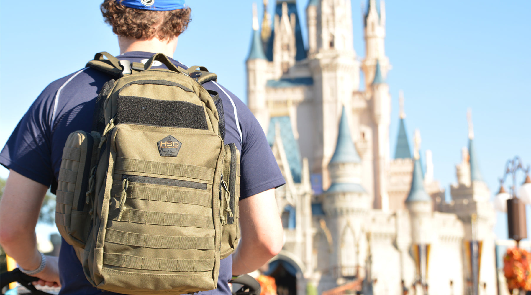 Person wearing a green backpack with a castle in the background