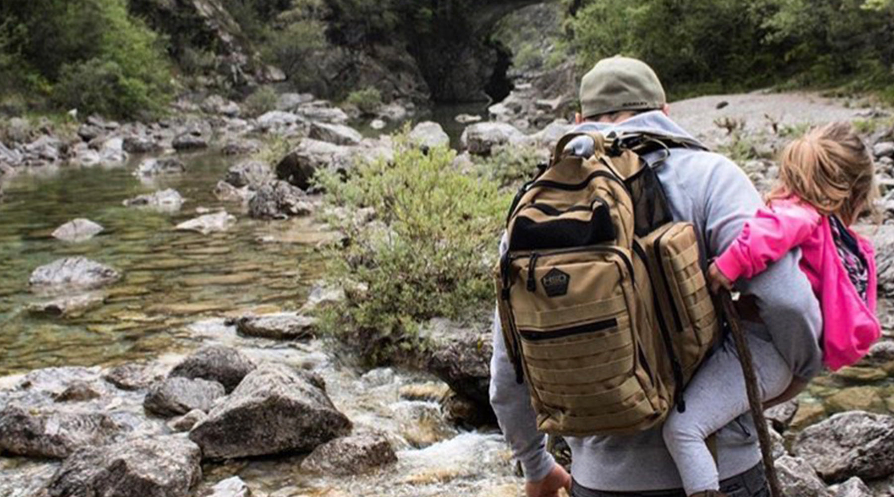 Person with a large backpack hiking near a river