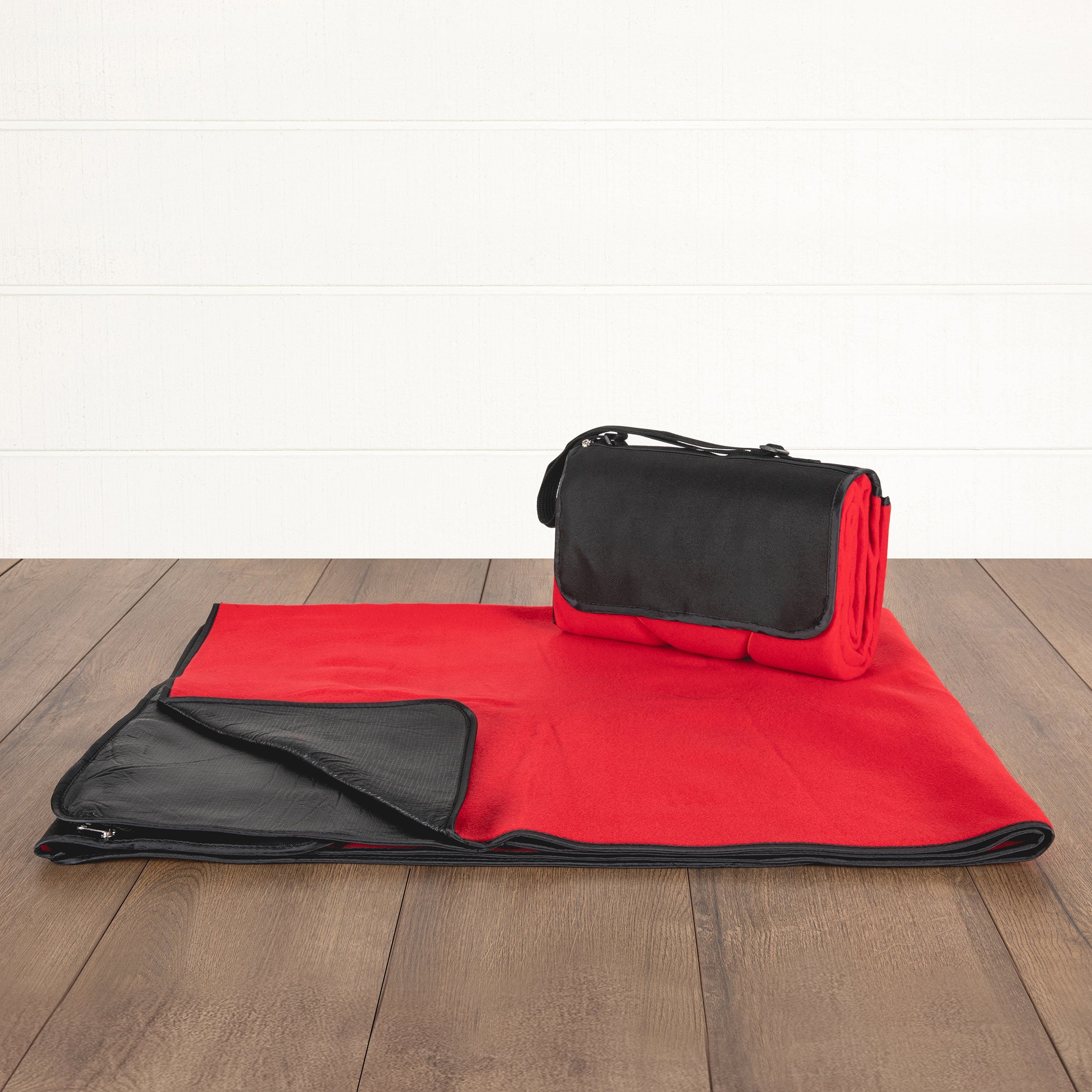 Red and black blanket with a matching bag on a wooden floor.