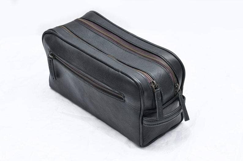 Black leather toiletry bag with zippers on a white background