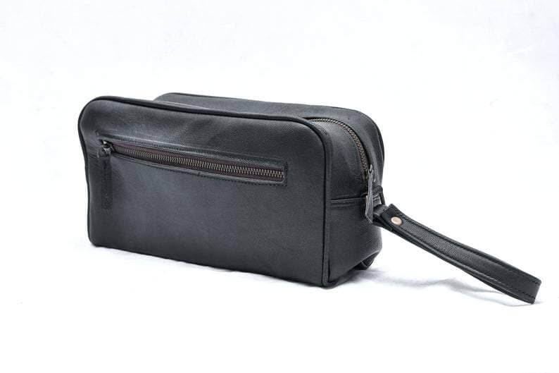 Black leather toiletry bag with a strap on a white background