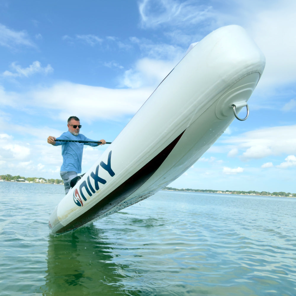 Person on a white inflatable kayak with 'Nixy' branding on a calm body of water.