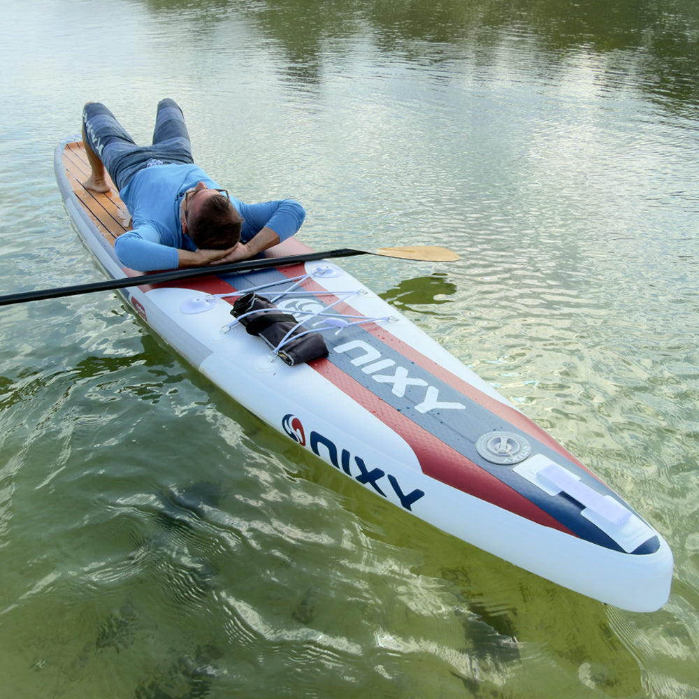 Person lying on a NIXY inflatable paddleboard on a lake