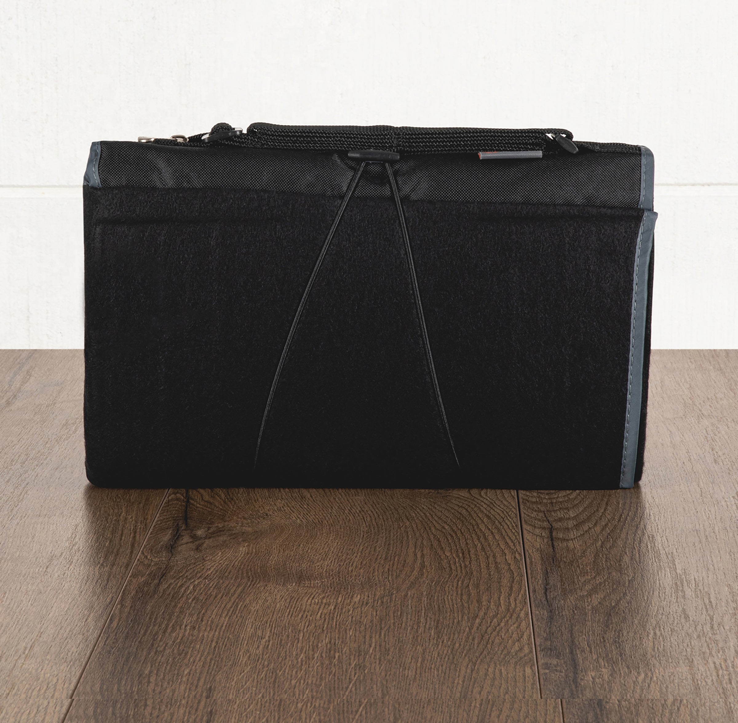 Black duffel bag with a strap on a wooden floor