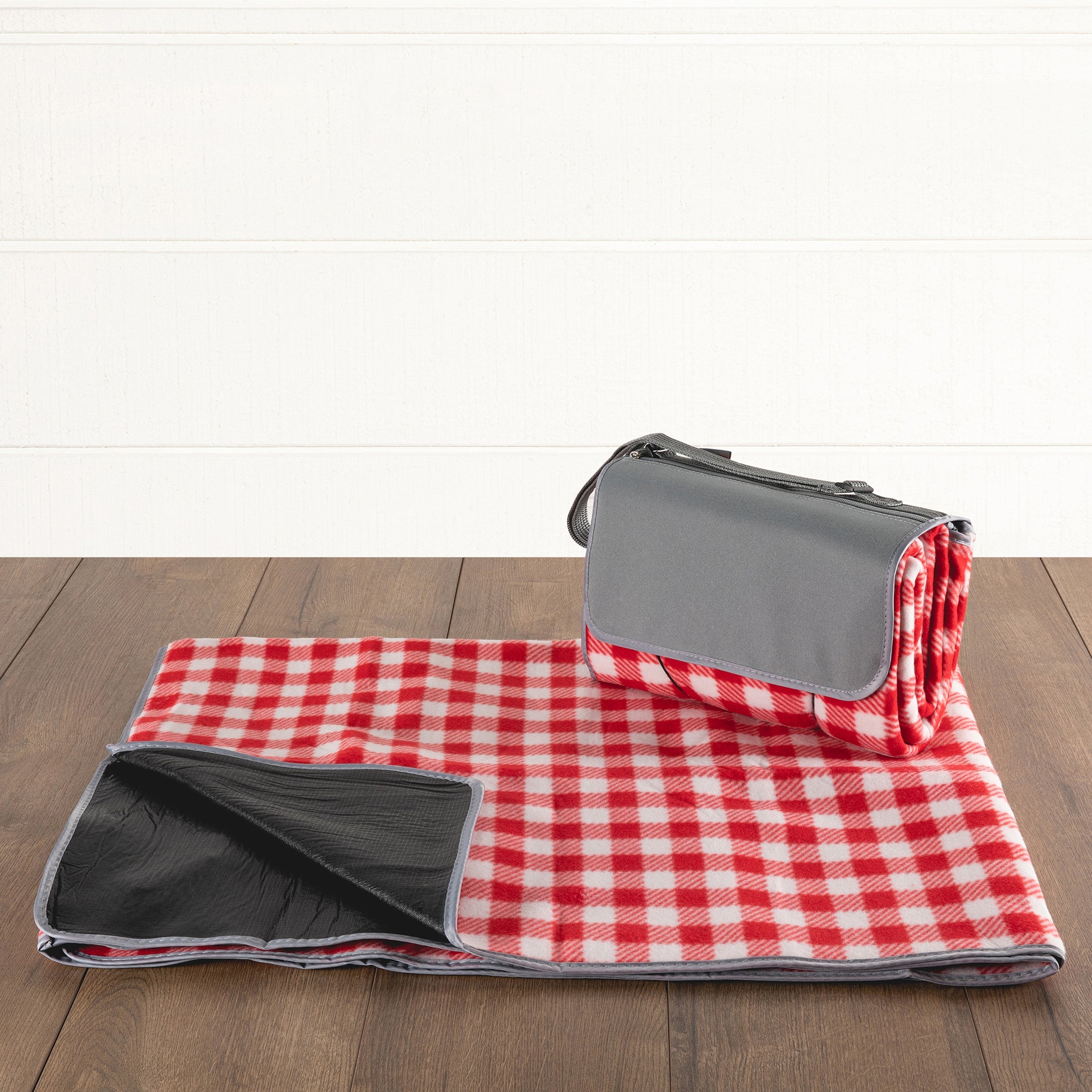 Red and white checkered picnic blanket with gray border on a wooden surface