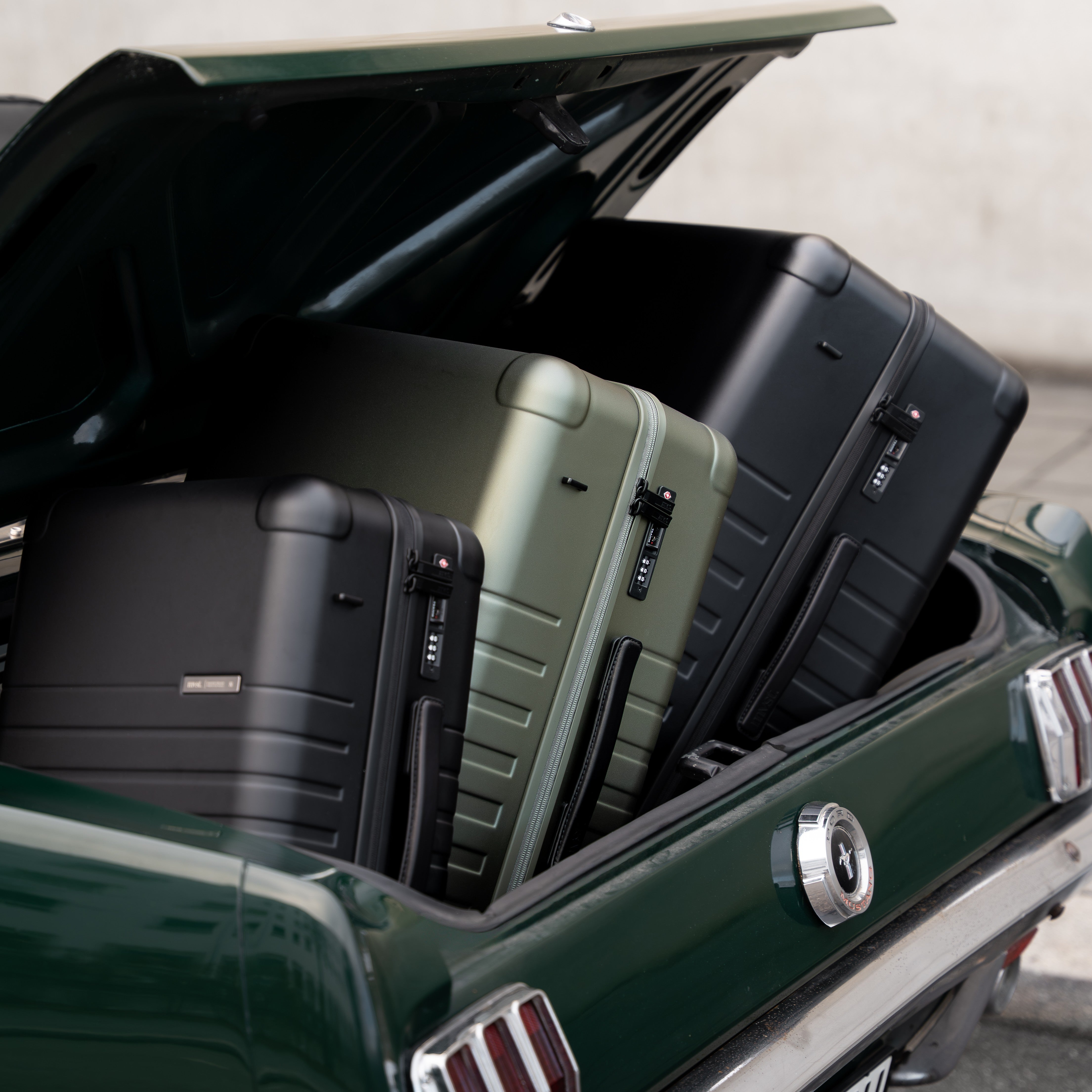 Three suitcases in a car trunk with a neutral background