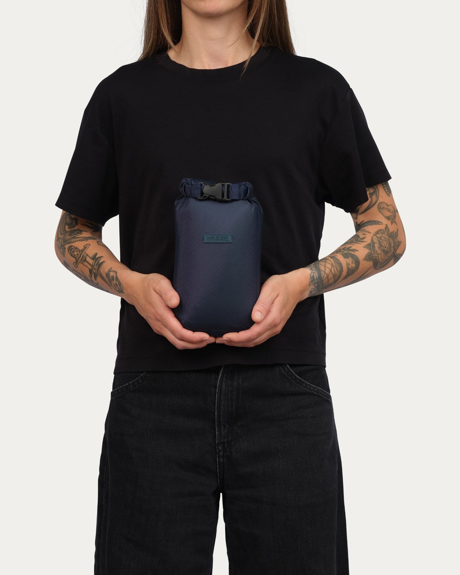 Person holding a navy blue bag against a plain background