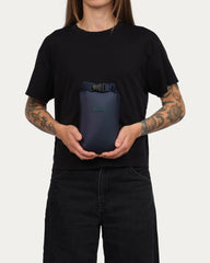 Person holding a navy blue bag against a plain background