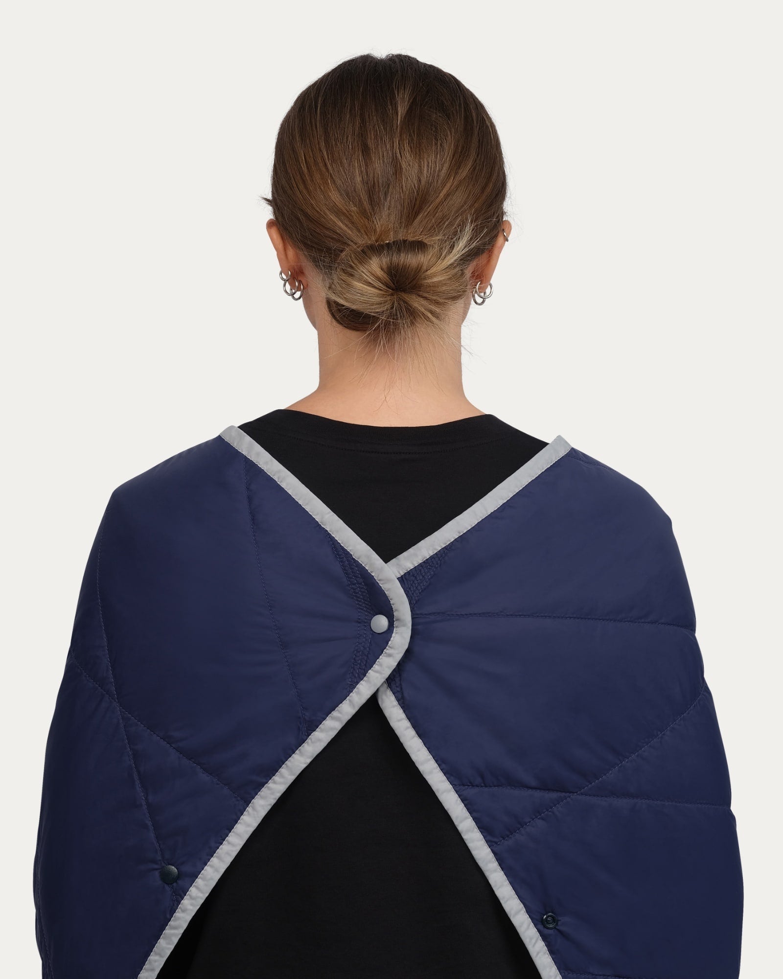 Person wearing a navy blue quilted jacket with gray trim on a white background