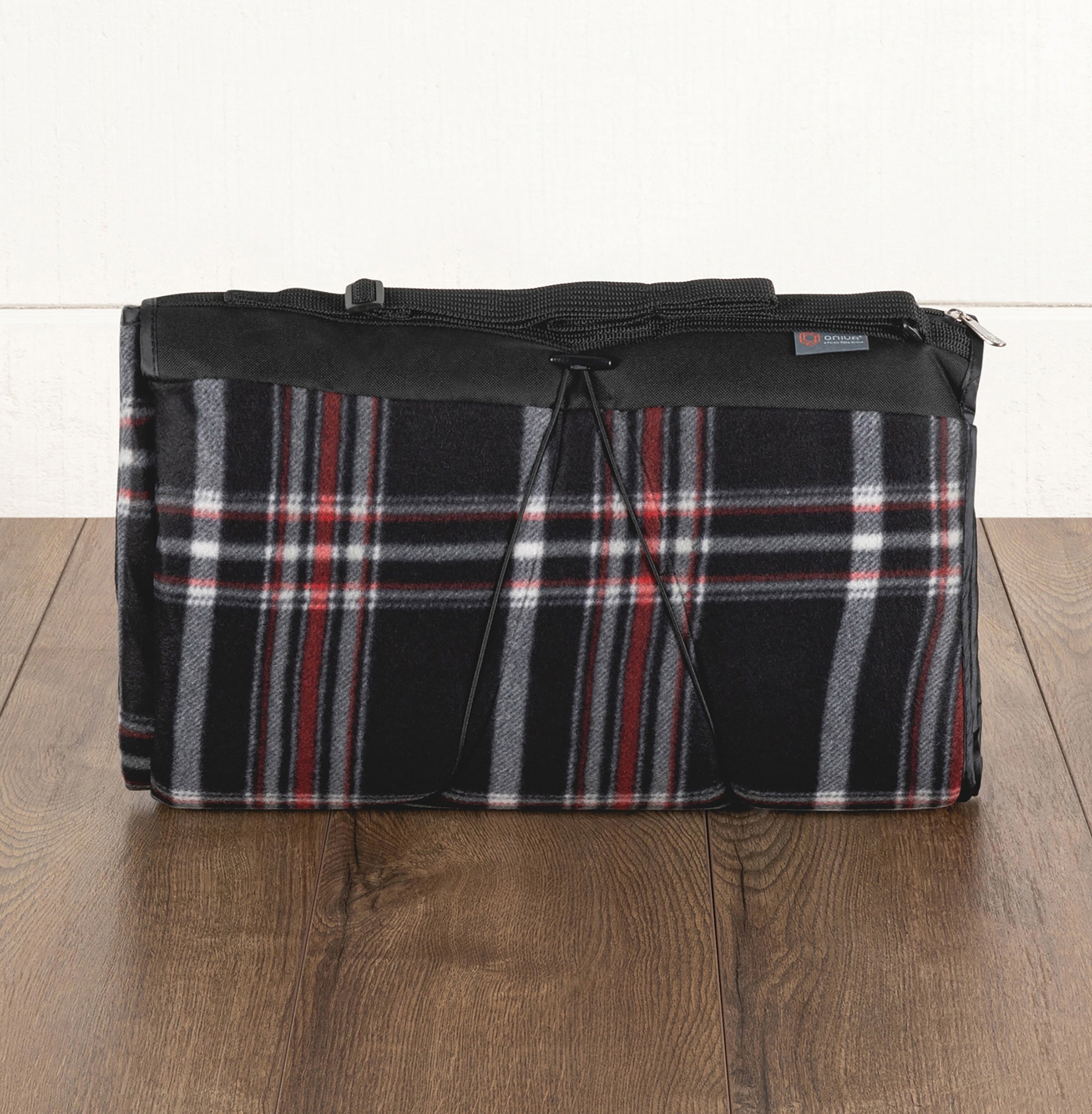 Plaid-patterned bag with black trim on a wooden floor