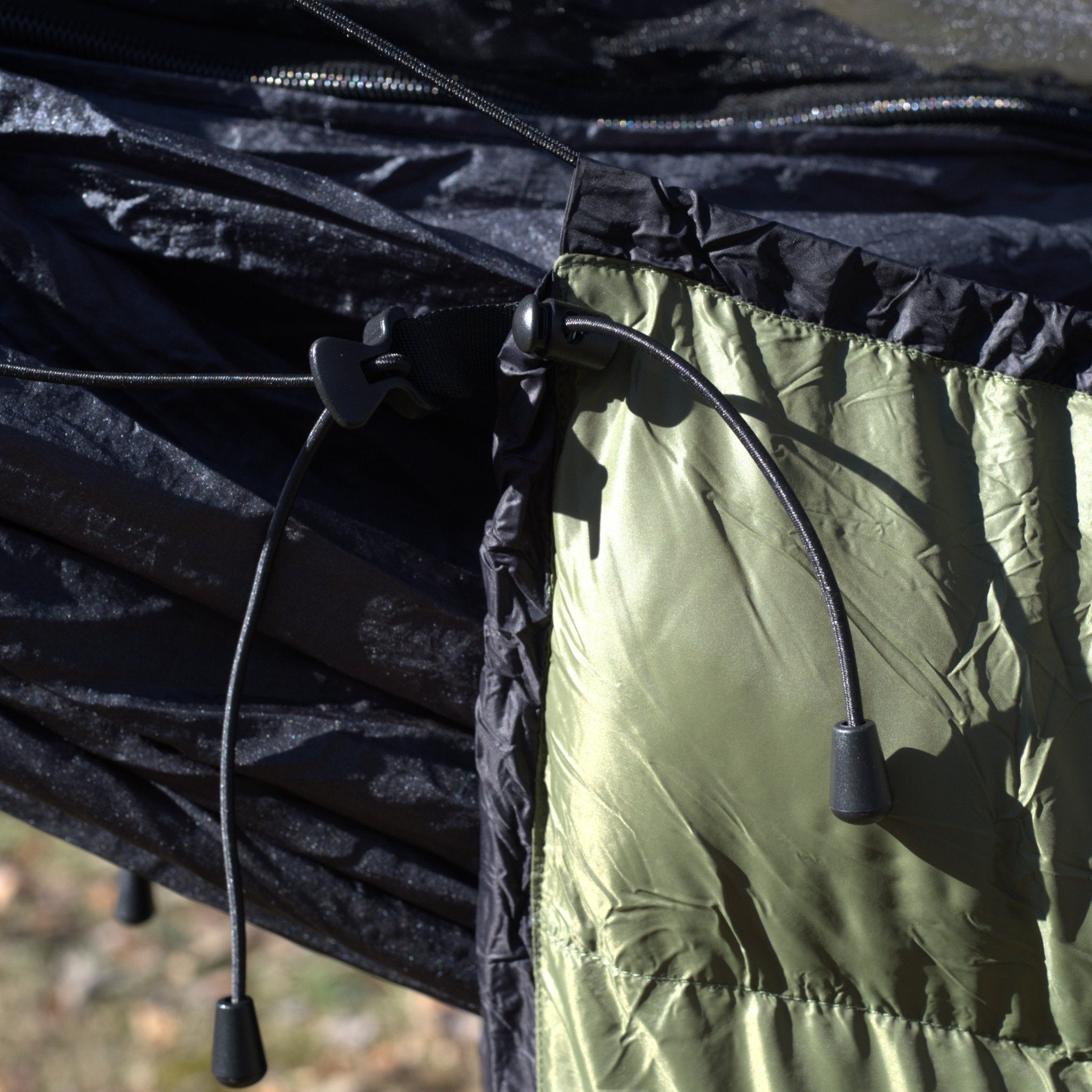 Close-up of a black and green fabric with drawstrings on a blurred natural background