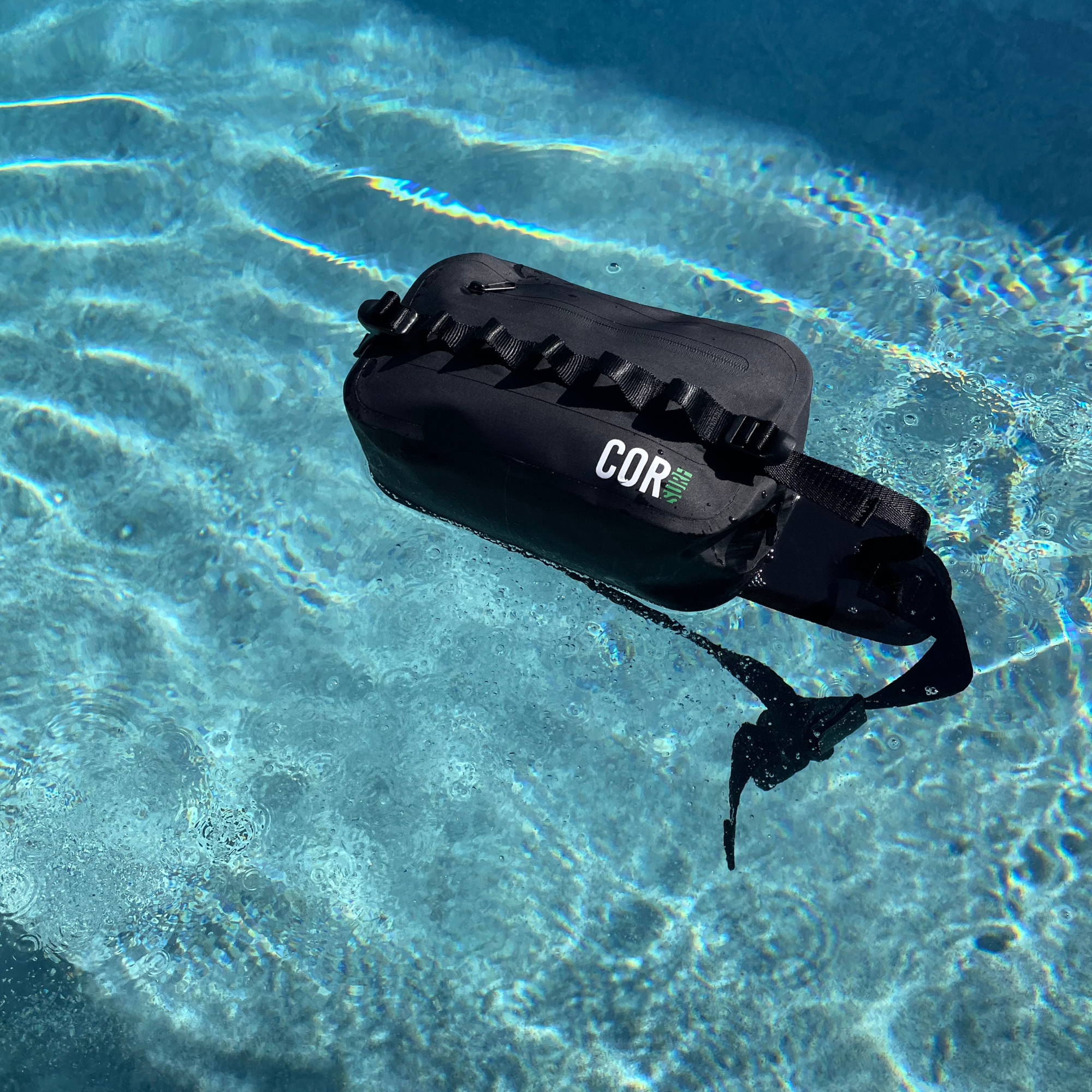 Black inflatable device labeled 'COR' floating in clear blue water.